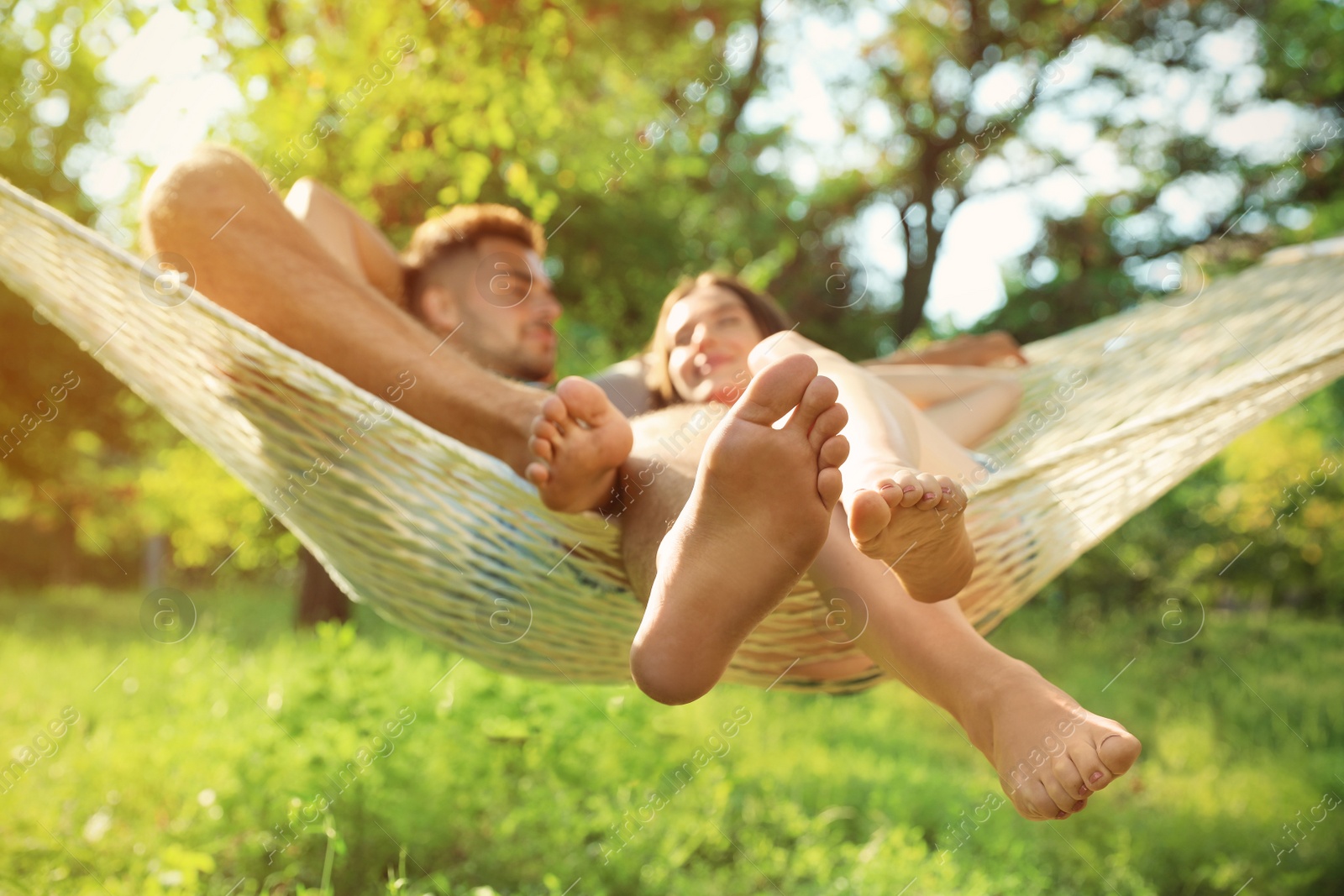 Photo of Young couple resting in comfortable hammock at green garden