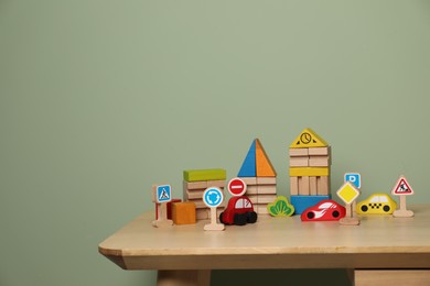 Photo of Set of different wooden toys on table near olive wall, space for text. Children's development