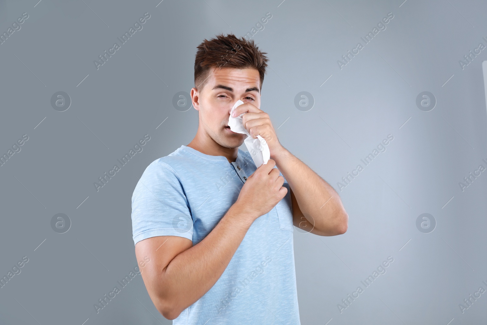 Photo of Young man suffering from allergy on grey background