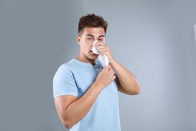 Photo of Young man suffering from allergy on grey background