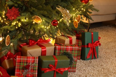 Many gift boxes under Christmas tree in room