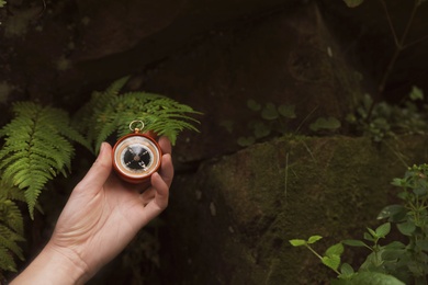 Traveler searching direction with compass in wilderness, closeup. Space for text