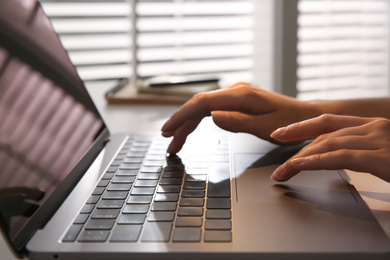 Woman working with modern laptop indoors, closeup