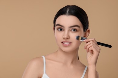 Photo of Teenage girl with makeup brush on beige background