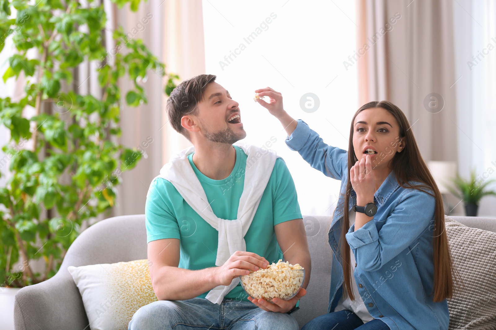 Photo of Couple watching movie with popcorn in living room