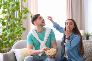 Couple watching movie with popcorn in living room