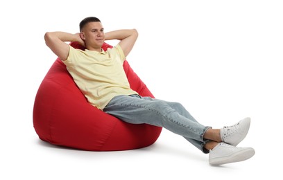 Photo of Handsome man resting on red bean bag chair against white background