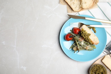 Photo of Delicious baked green beans served on grey table, flat lay. Space for text