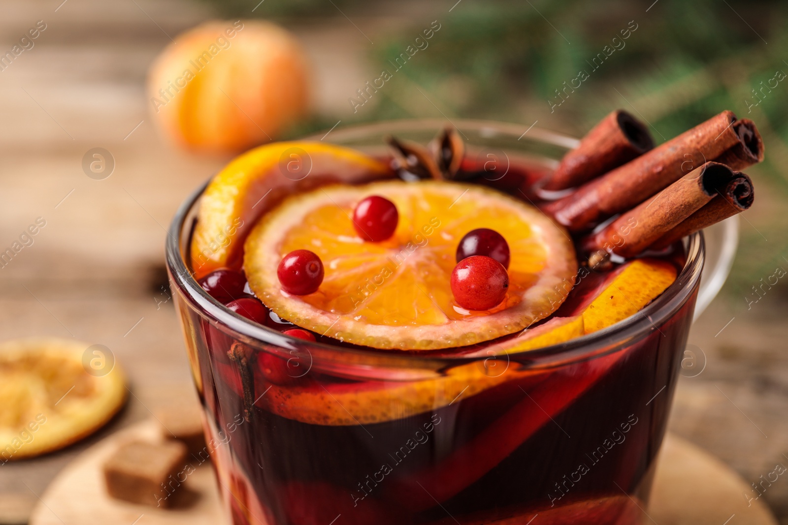 Photo of Glass cup with tasty mulled wine on table, closeup