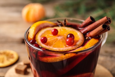 Photo of Glass cup with tasty mulled wine on table, closeup