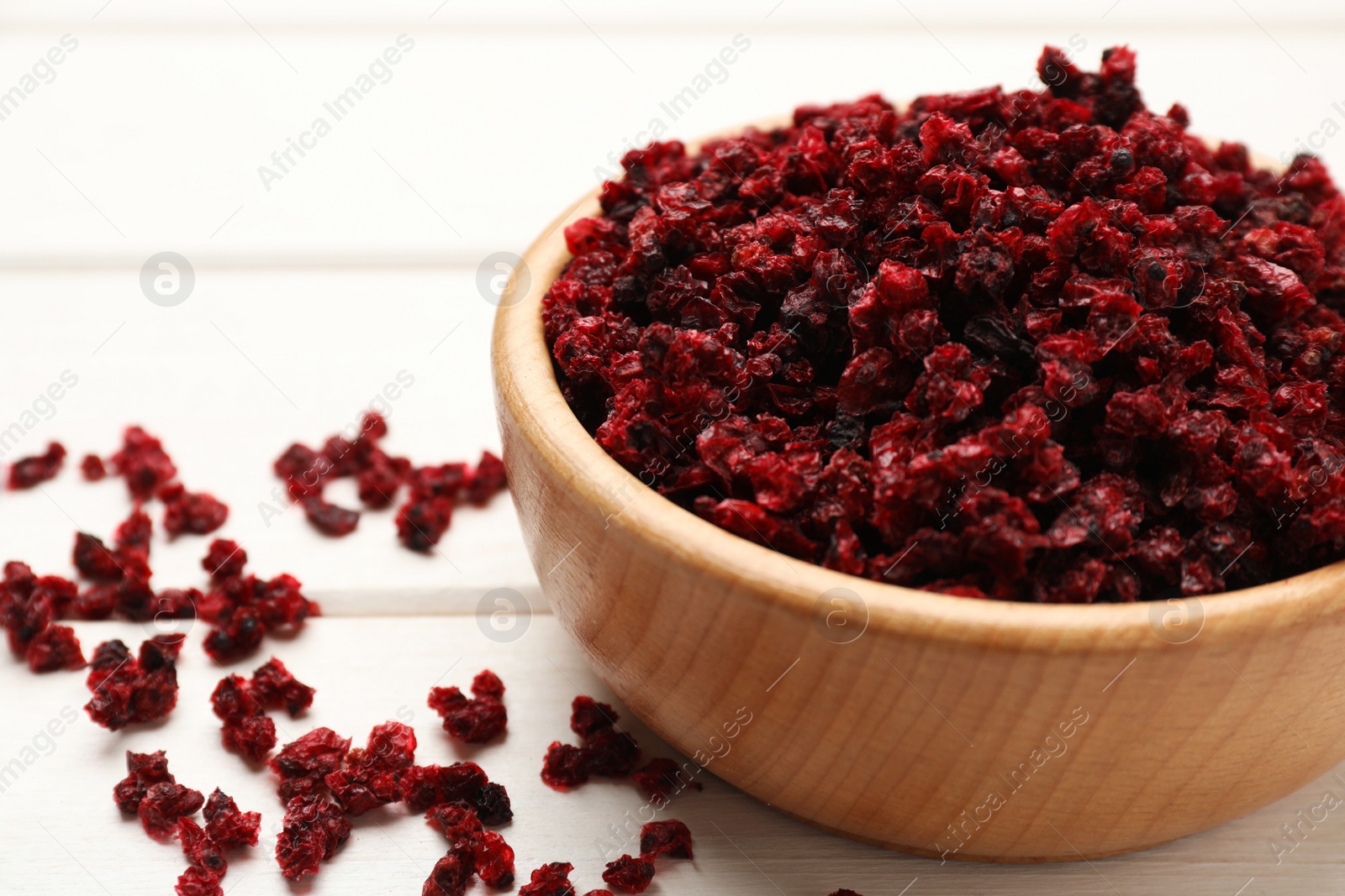 Photo of Wooden bowl and dried red currant berries on white table, closeup