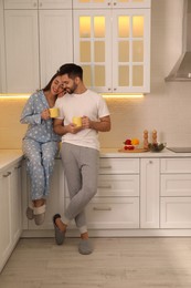 Happy couple in pajamas having breakfast at home