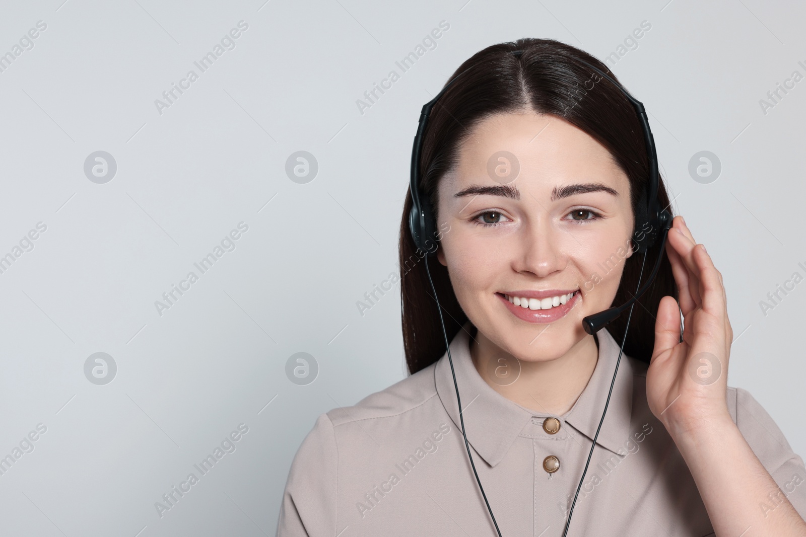 Photo of Hotline operator with modern headset on light grey background, space for text. Customer support