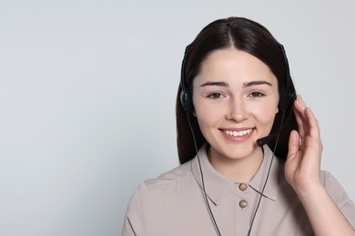 Hotline operator with modern headset on light grey background, space for text. Customer support