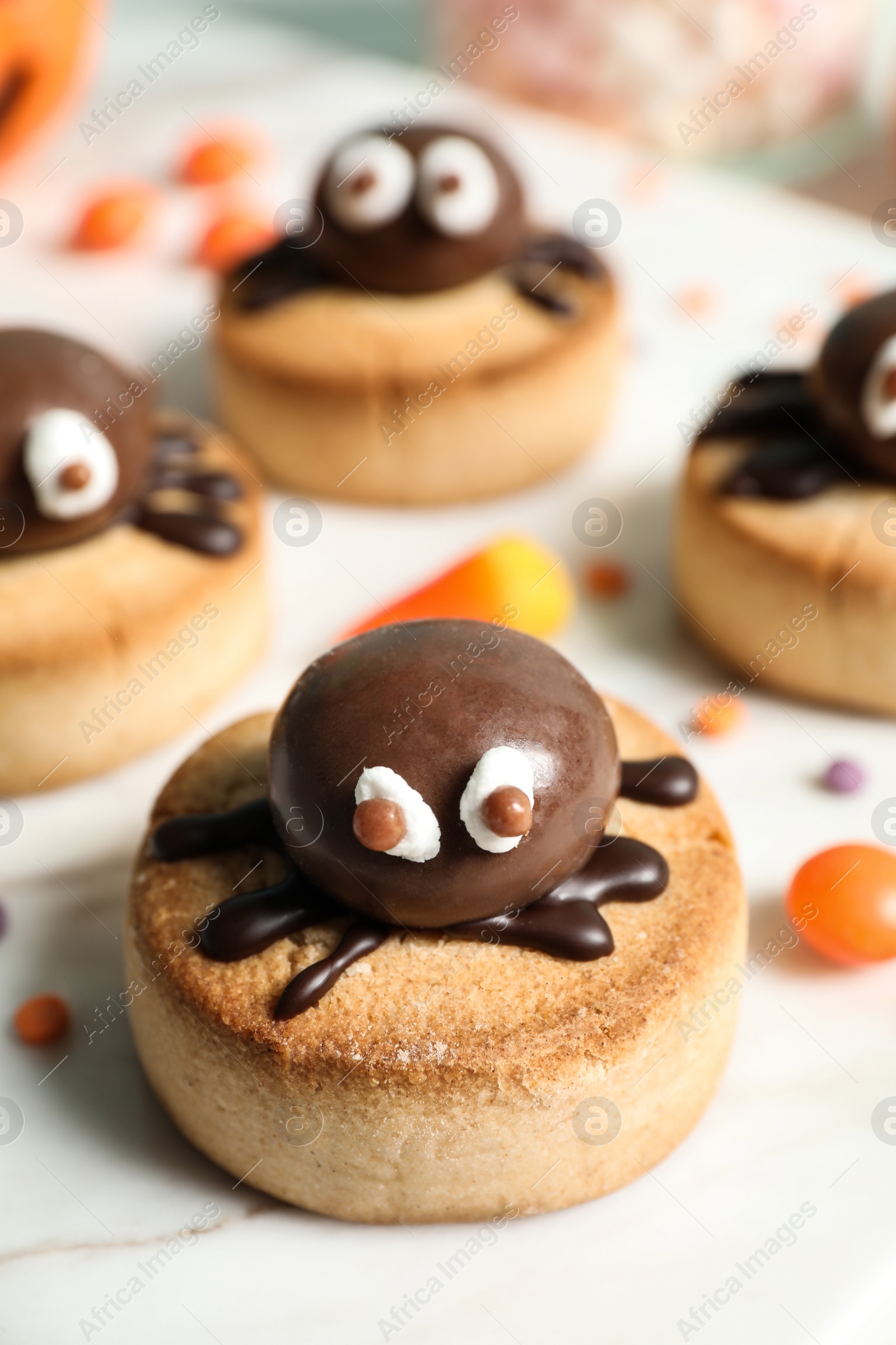 Photo of Delicious biscuit with chocolate spider on white table, closeup. Halloween celebration