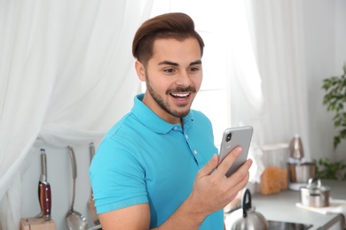 Young man laughing while using smartphone at home