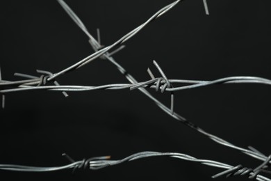 Photo of Metal barbed wire on dark grey background, closeup