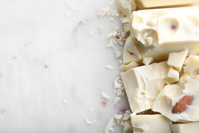 Photo of Pieces of white chocolate with nuts on light table, flat lay. Space for text