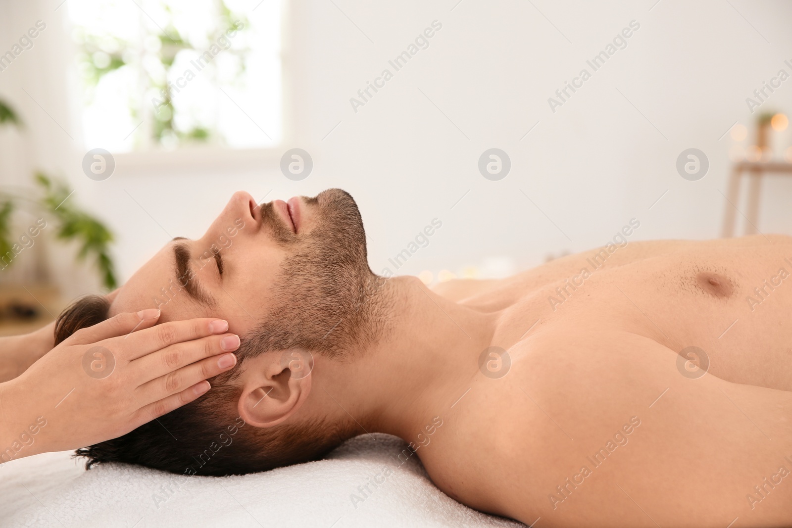 Photo of Handsome man receiving face massage in spa salon
