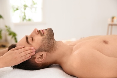 Handsome man receiving face massage in spa salon