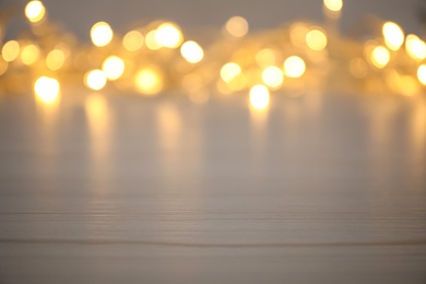 Photo of Blurred view of gold lights on white table, space for text