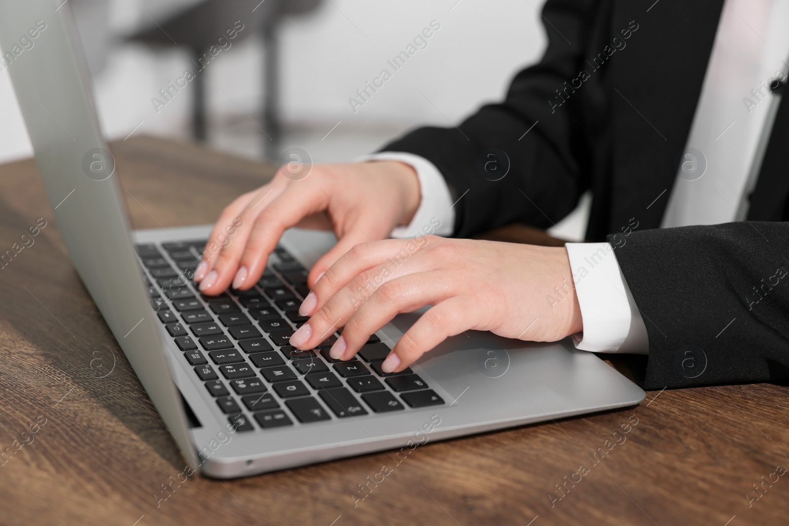 Photo of Woman working on laptop at wooden table closeup. Electronic document management