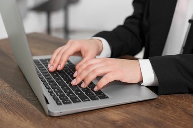 Photo of Woman working on laptop at wooden table closeup. Electronic document management