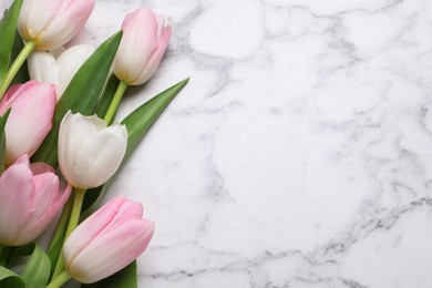 Beautiful tulips  on white marble table, flat lay. Space for text