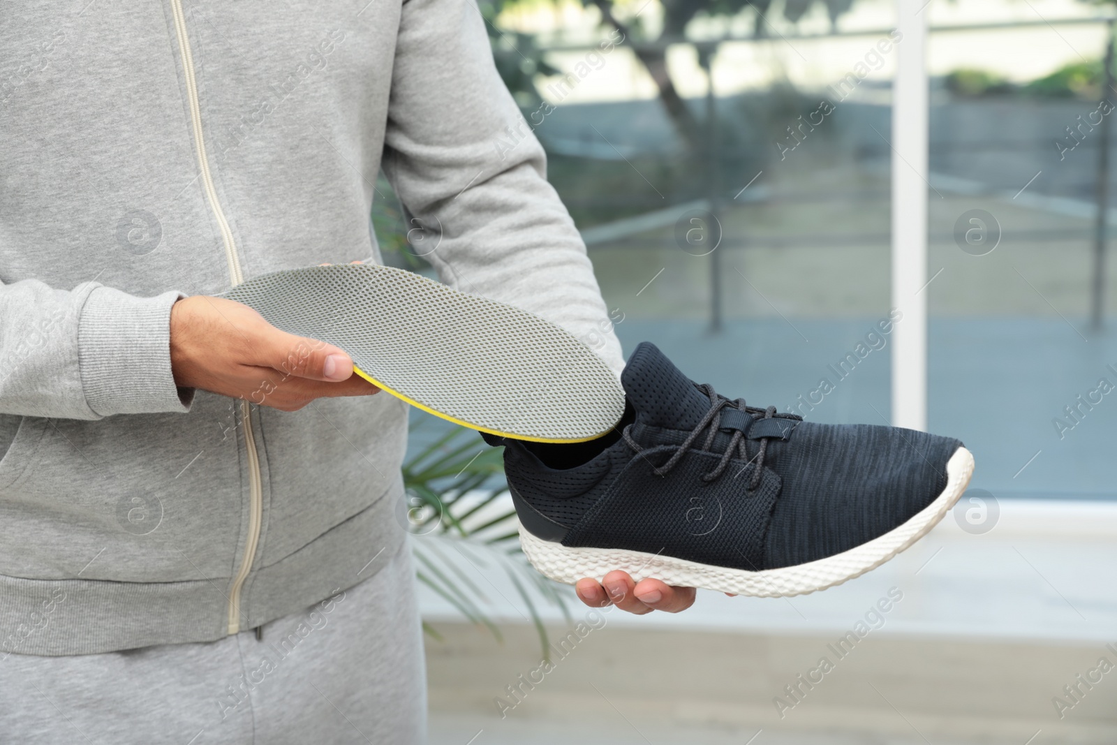 Photo of Man putting orthopedic insole into shoe indoors, closeup. Foot care