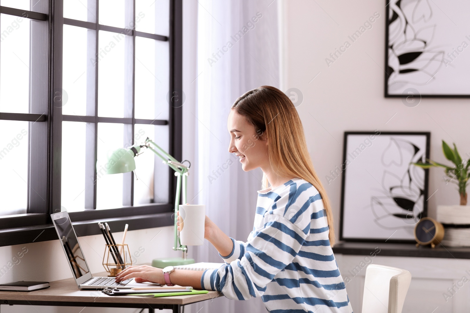 Photo of Teenage girl using laptop at table in her room