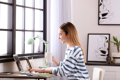 Teenage girl using laptop at table in her room