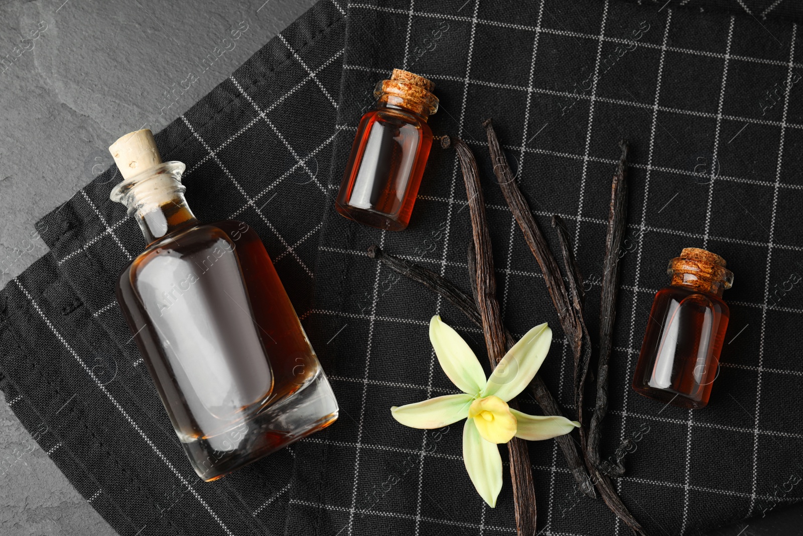 Photo of Flat lay composition with vanilla extract on black table