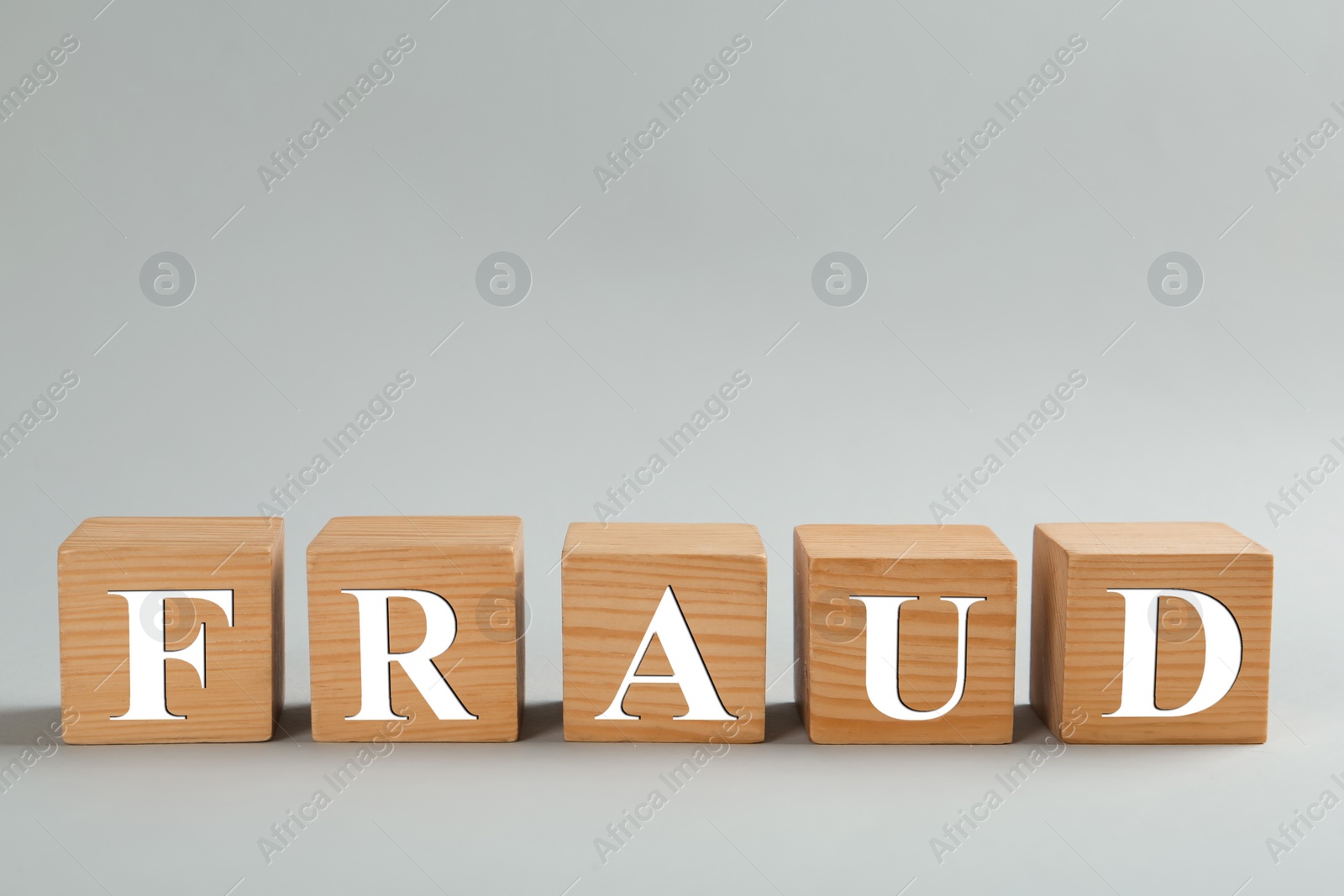 Photo of Wooden cubes with word Fraud on grey background, space for text