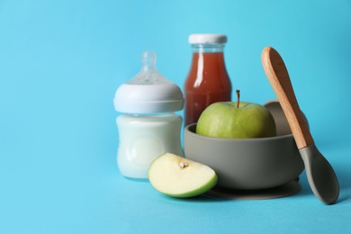 Healthy baby food, milk, apples and spoon on light blue background. Space for text