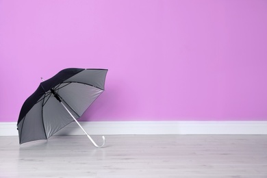 Photo of Beautiful open umbrella on floor near color wall with space for design