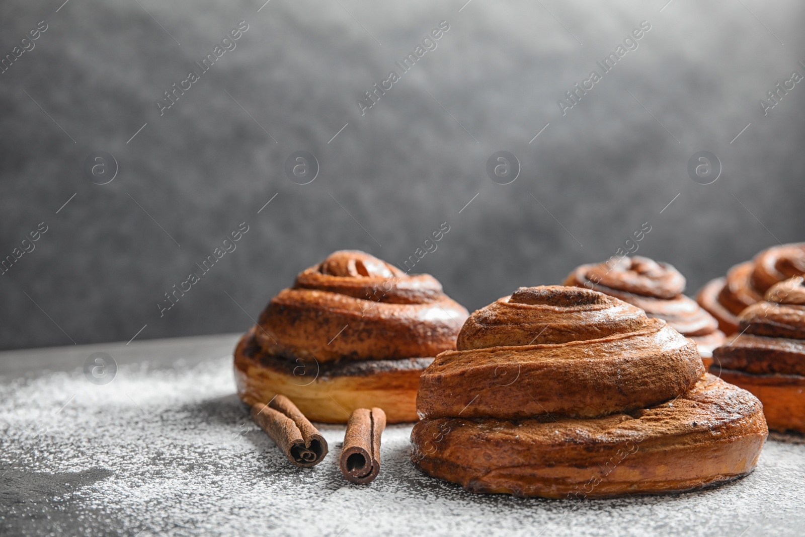 Photo of Cinnamon rolls and sugar powder on table. Space for text