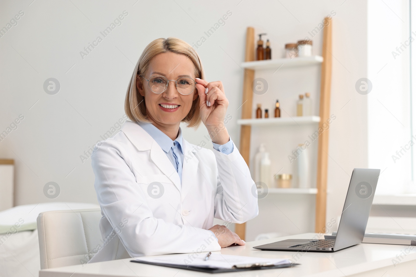 Photo of Portrait of happy dermatologist at white table in clinic