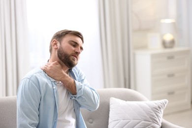 Photo of Man suffering from neck pain at home. Bad posture problem