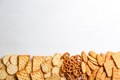Photo of Many delicious crackers on white wooden table, flat lay. Space for text