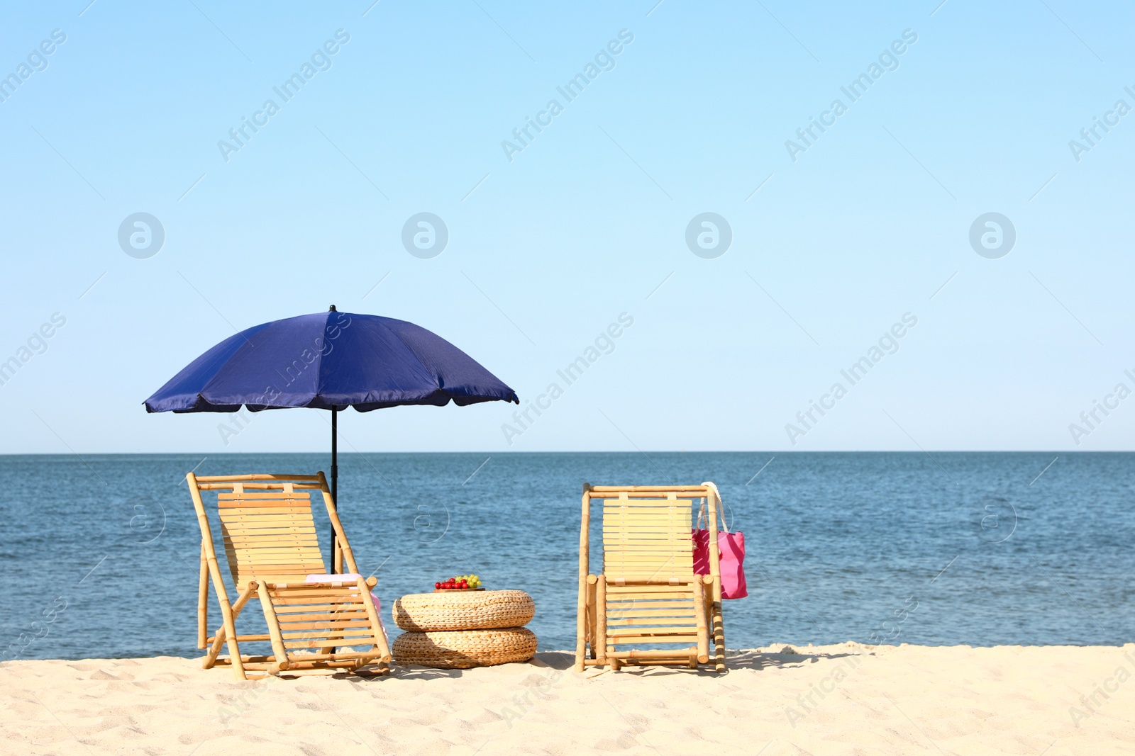 Photo of Empty wooden sunbeds and beach accessories on sandy shore