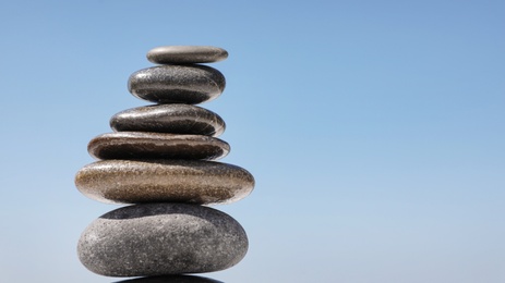 Photo of Stack of stones against blue sky, space for text. Zen concept