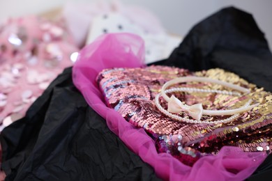 Photo of Headbands and stylish pink carnival costume with sequins in black box, closeup