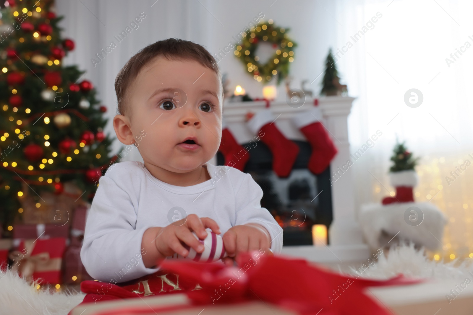 Photo of Portrait of cute baby with toy in room decorated for Christmas