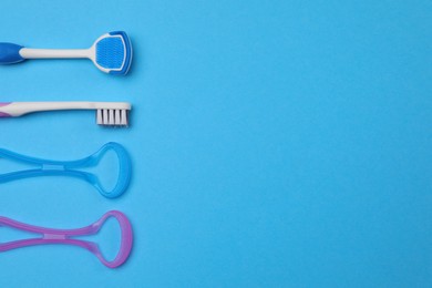 Photo of Tongue cleaners and toothbrush on blue background, flat lay. Space for text