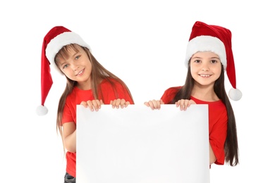 Photo of Cute little children in Santa hats with blank poster on white background. Christmas celebration
