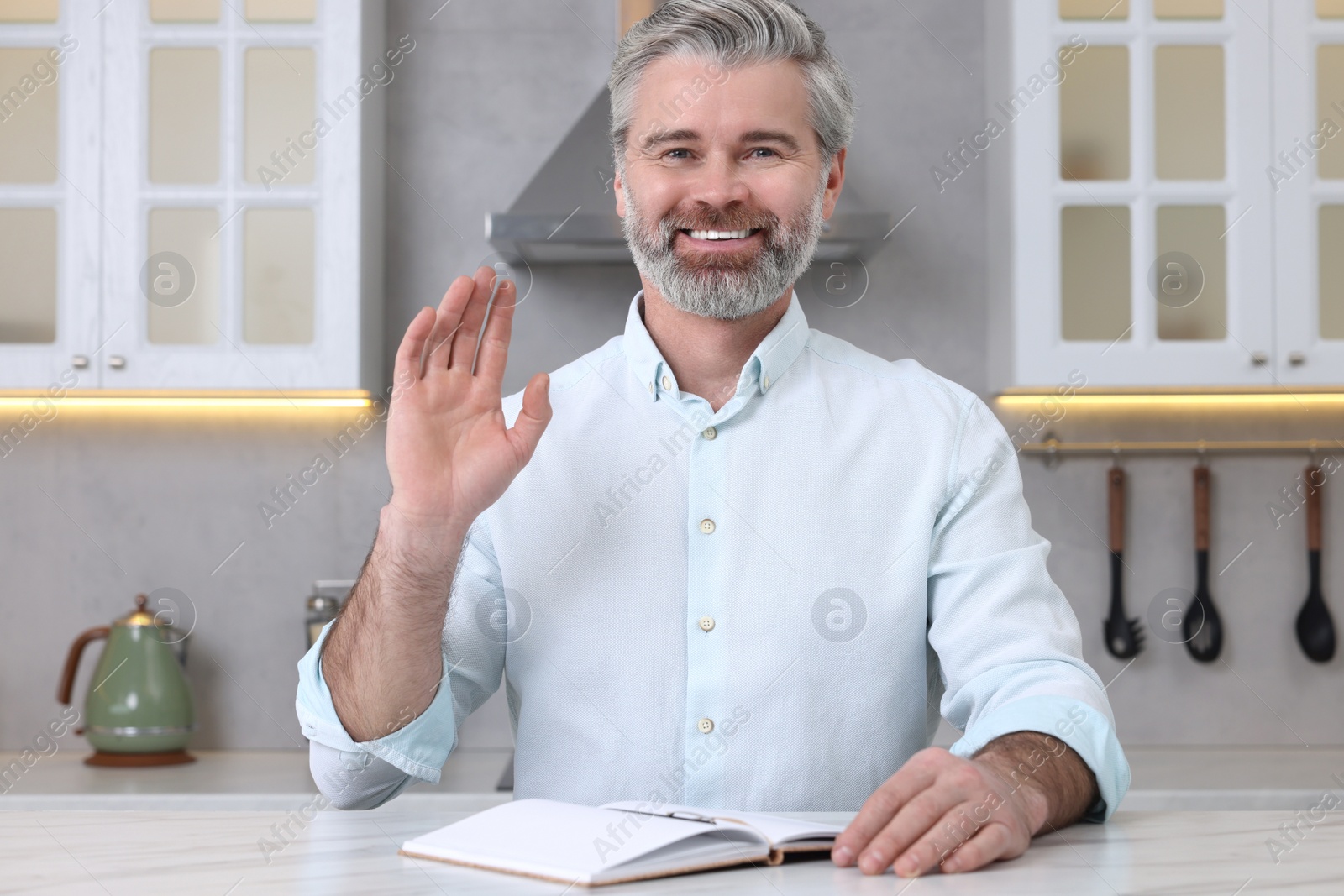 Photo of Man waving hello during video chat at home, view from webcam