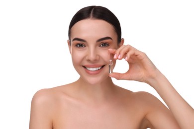 Beautiful young woman holding skincare ampoule on white background