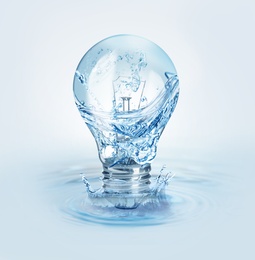 Image of Light bulb with water splashes on light background. Alternative energy source