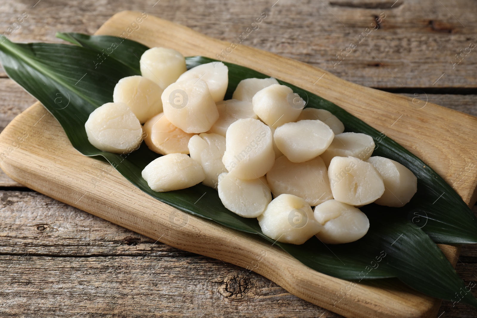 Photo of Fresh raw scallops on wooden table. Seafood