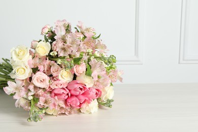 Beautiful bouquet of fresh flowers on table near white wall. Space for text